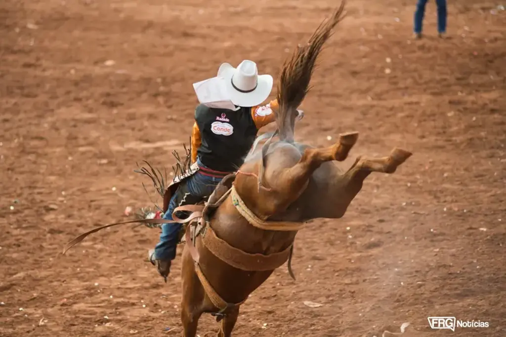 Peão de rodeio montado em cavalo durante prova de estilo Cutiano na Expo Fazenda. O animal aparece saltando com as patas traseiras para cima em arena de terra. Foto de Érico Andrade/G1.